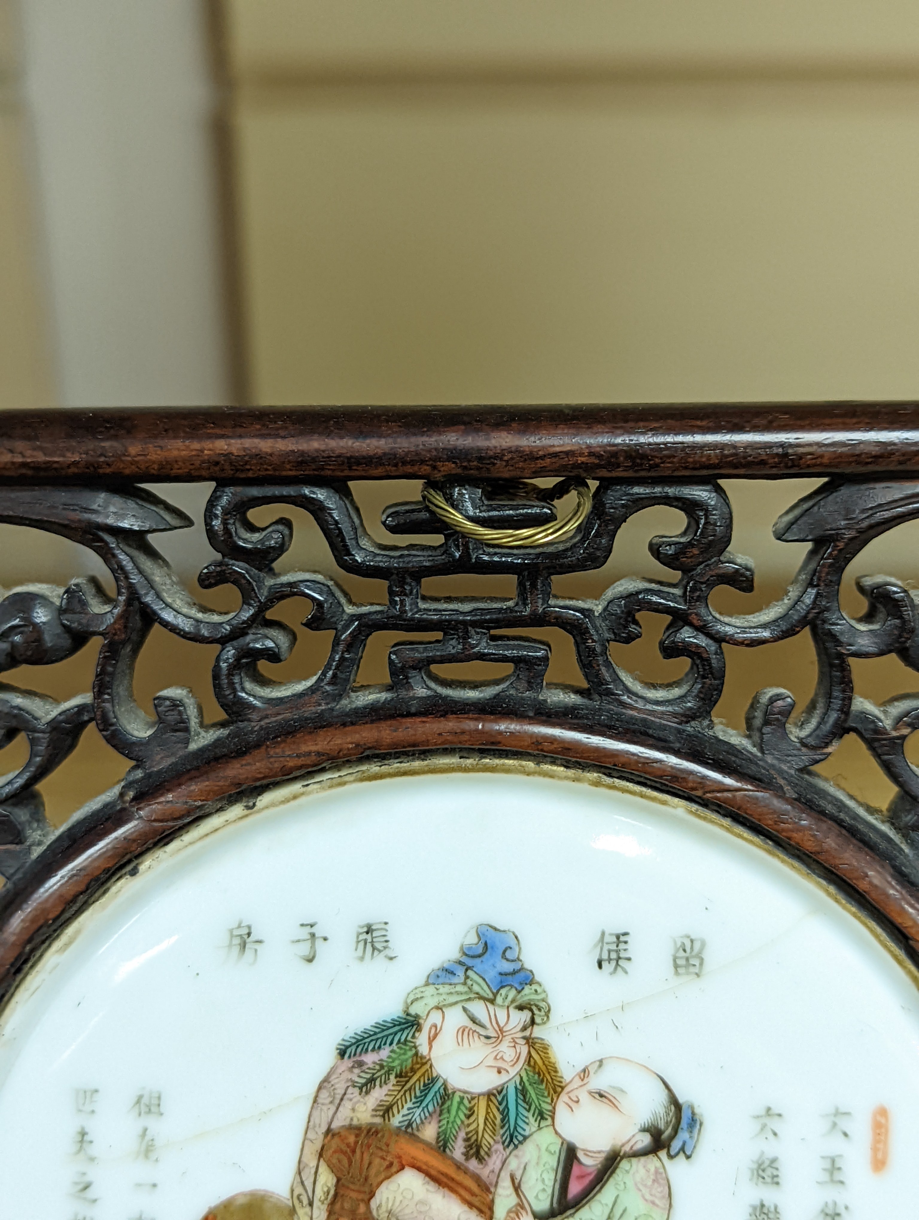 A 19th century Chinese famille rose circular plaque or cover, inset into a wood surround, cracks 15cm sq